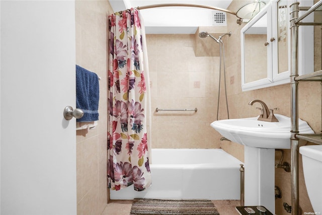 full bathroom featuring shower / tub combo with curtain, sink, tile walls, tile patterned flooring, and toilet