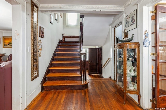 stairs featuring wood-type flooring, vaulted ceiling, and ornamental molding