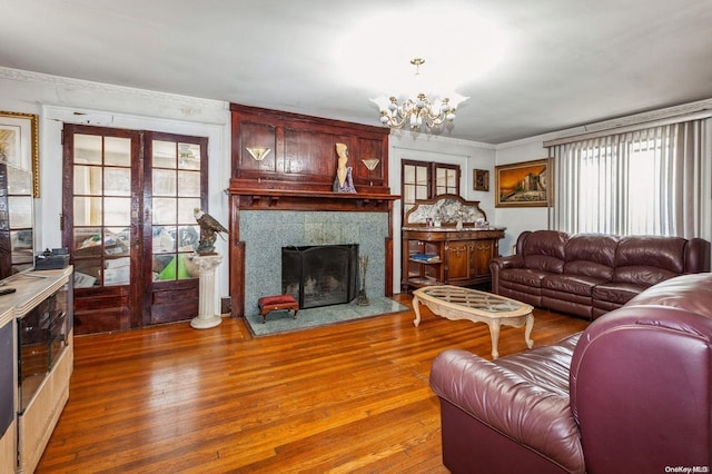 living room featuring a fireplace, wood-type flooring, plenty of natural light, and a notable chandelier