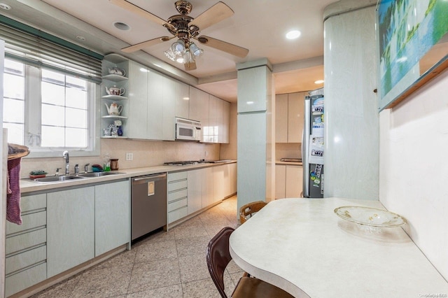 kitchen with decorative backsplash, appliances with stainless steel finishes, ceiling fan, sink, and white cabinets