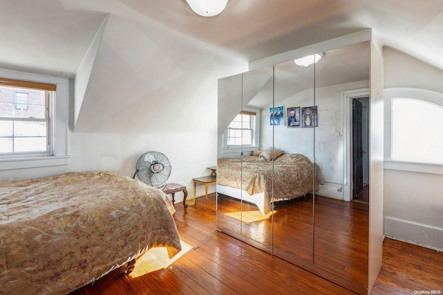 bedroom with hardwood / wood-style flooring, vaulted ceiling, and multiple windows