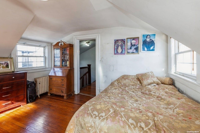 bedroom with multiple windows, dark hardwood / wood-style flooring, radiator, and lofted ceiling