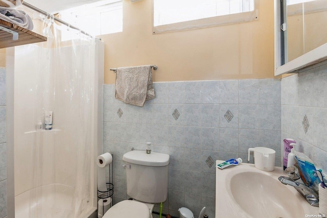 bathroom with a shower with curtain, toilet, tile walls, and sink