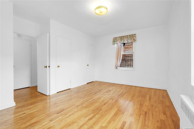 unfurnished room with light wood-type flooring and radiator