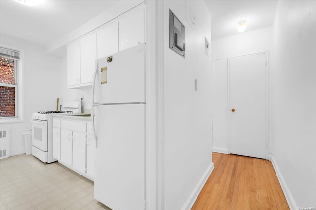 kitchen with light wood-type flooring, radiator heating unit, white appliances, and white cabinetry