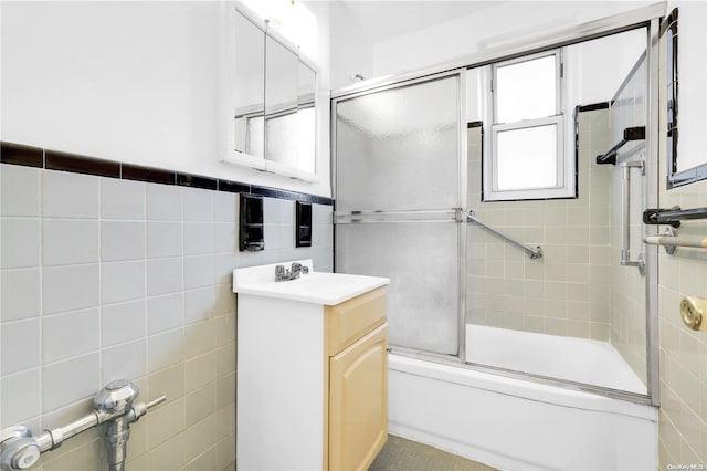 bathroom with combined bath / shower with glass door, vanity, and tile walls