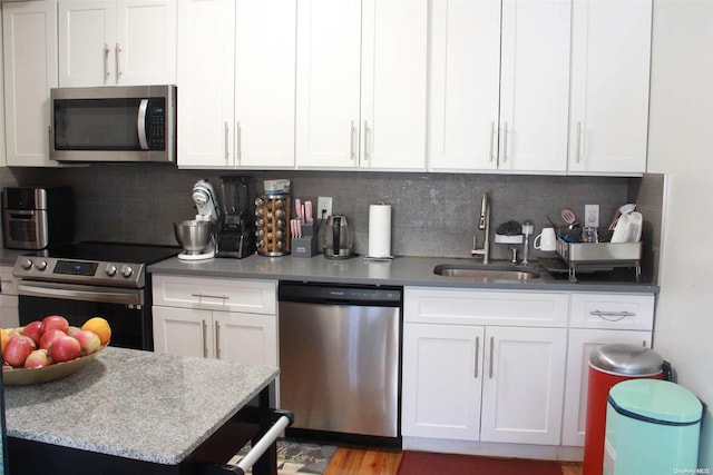 kitchen with backsplash, sink, white cabinetry, and stainless steel appliances