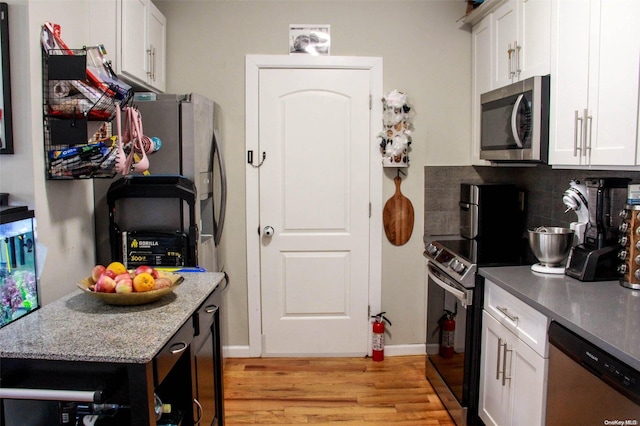 kitchen featuring backsplash, white cabinets, stainless steel appliances, and light wood-type flooring