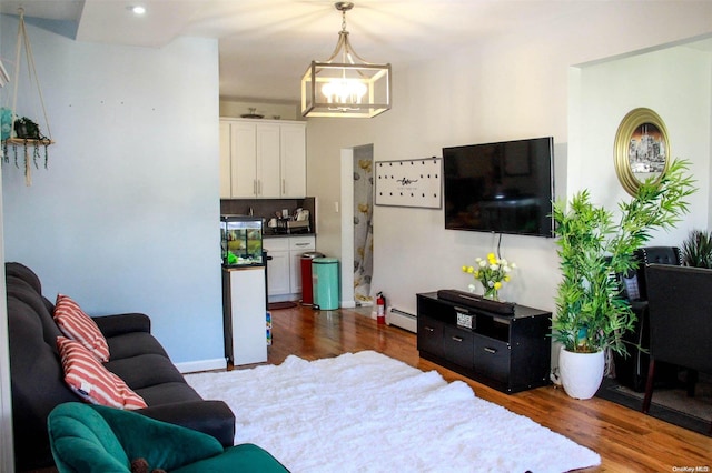 living room featuring a notable chandelier, baseboard heating, and dark wood-type flooring