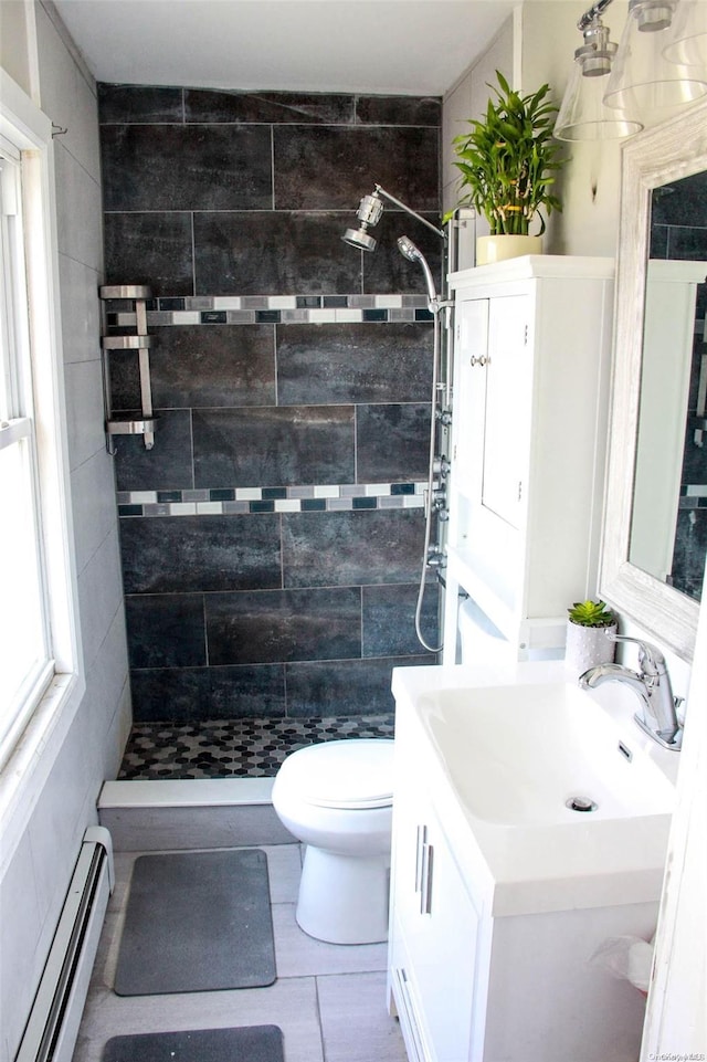 bathroom featuring a tile shower, a baseboard radiator, toilet, vanity, and tile walls