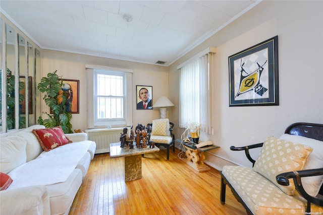 sitting room featuring radiator, hardwood / wood-style floors, and ornamental molding