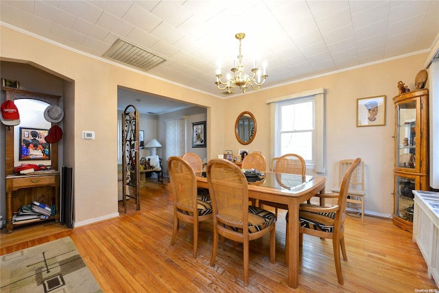 dining space featuring light wood-type flooring, crown molding, and a chandelier