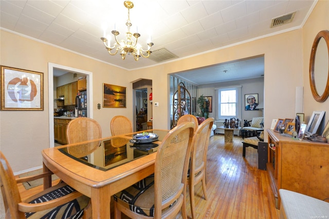 dining room with crown molding, a chandelier, and hardwood / wood-style flooring