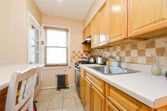 kitchen featuring sink, radiator heating unit, tasteful backsplash, light tile patterned floors, and stainless steel range with gas stovetop