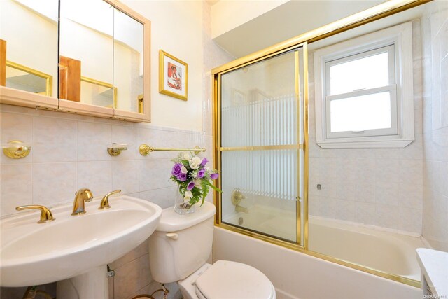 full bathroom with sink, enclosed tub / shower combo, tile walls, and toilet