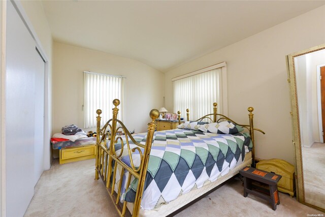 bedroom with multiple windows, light colored carpet, and lofted ceiling