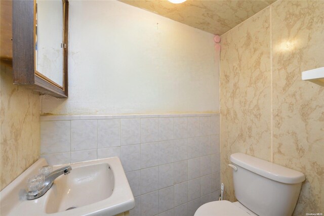 bathroom featuring sink, tile walls, and toilet