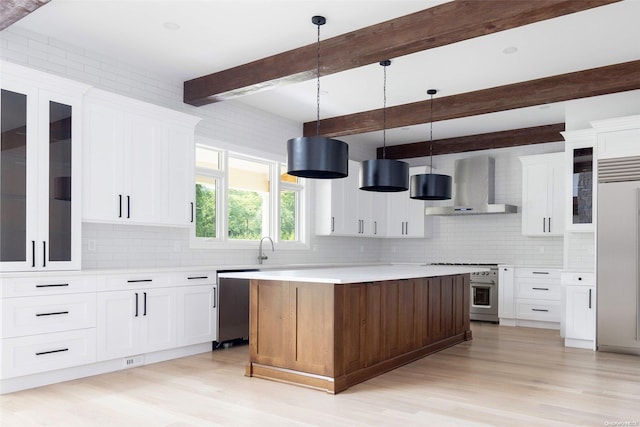 kitchen with beam ceiling, high end appliances, hanging light fixtures, and wall chimney exhaust hood