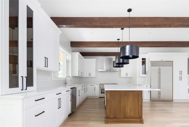 kitchen featuring a center island, high quality appliances, white cabinets, hanging light fixtures, and wall chimney exhaust hood