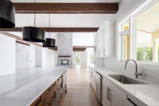 kitchen with beamed ceiling, a healthy amount of sunlight, white cabinetry, and sink