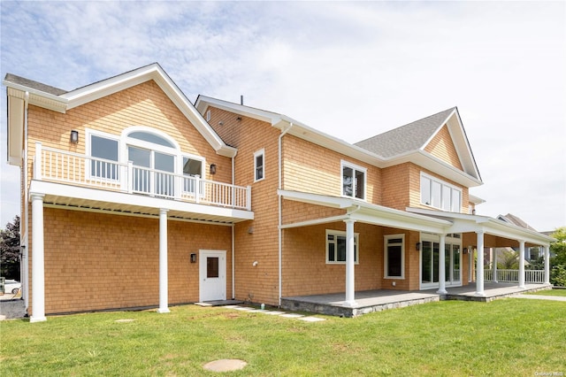 rear view of property with a lawn, a patio area, and a balcony