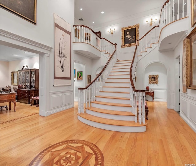 staircase with crown molding, hardwood / wood-style floors, and a high ceiling