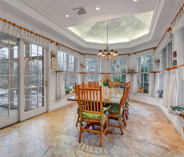 dining room with a healthy amount of sunlight, a raised ceiling, ornamental molding, and a chandelier