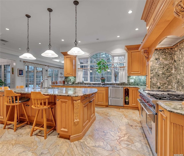 kitchen featuring a wealth of natural light, high end stove, a large island with sink, and tasteful backsplash