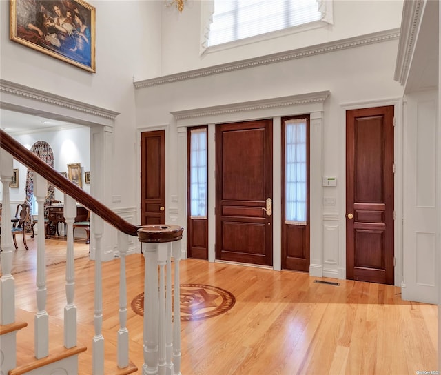 entrance foyer featuring crown molding, a towering ceiling, and wood-type flooring