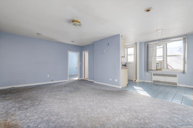 unfurnished living room featuring radiator heating unit and light carpet