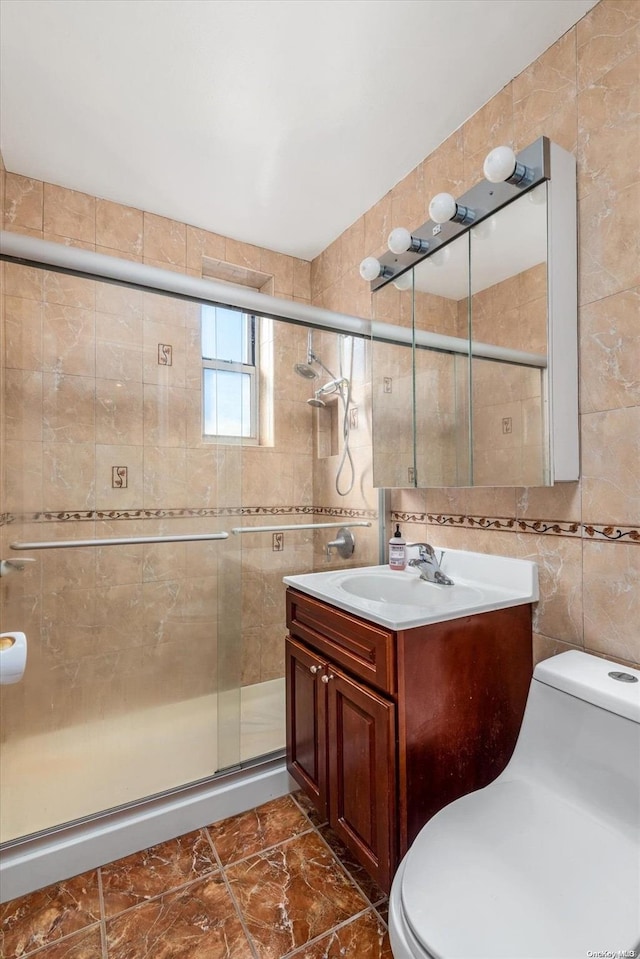 bathroom featuring vanity, a shower with door, toilet, and tile walls