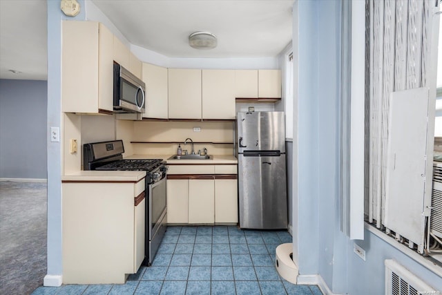 kitchen with cream cabinets, sink, light carpet, and appliances with stainless steel finishes