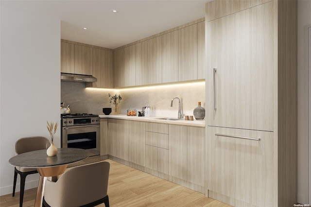 kitchen featuring light brown cabinetry, extractor fan, sink, light hardwood / wood-style flooring, and high end stainless steel range