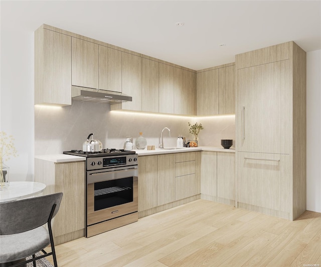 kitchen featuring light brown cabinets, backsplash, sink, light wood-type flooring, and high end stove