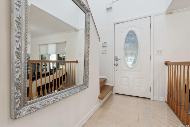 entryway with light tile patterned floors and crown molding