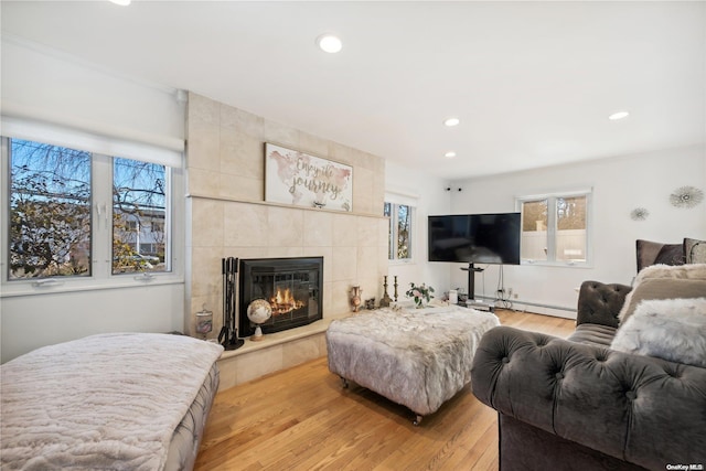 living room with a tile fireplace, light hardwood / wood-style flooring, and a baseboard radiator