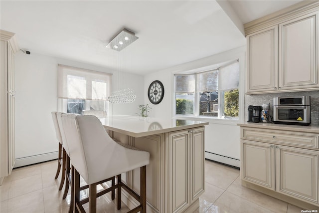 kitchen with a wealth of natural light, a center island, a baseboard heating unit, and cream cabinetry