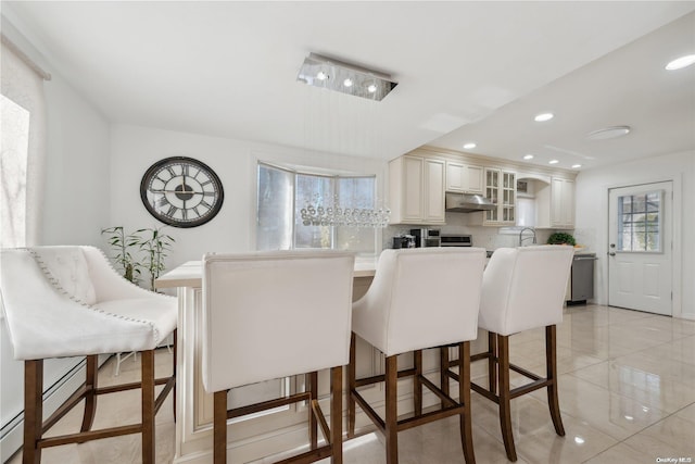 interior space with a breakfast bar, sink, cream cabinets, and tasteful backsplash