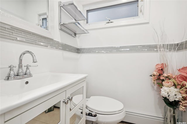 bathroom featuring tile patterned flooring, vanity, toilet, and a baseboard radiator