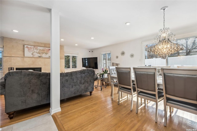 dining space with a tile fireplace and light wood-type flooring