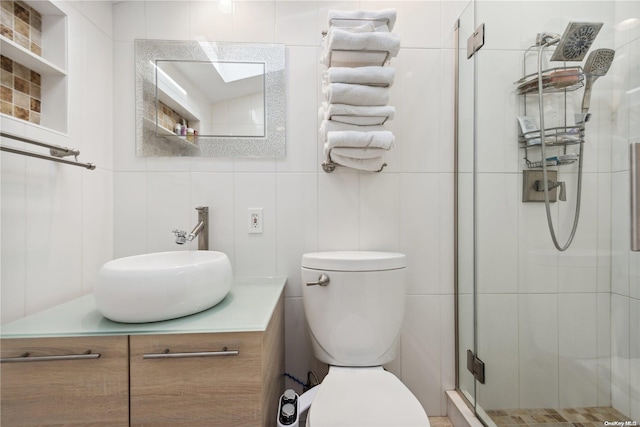 bathroom featuring vanity, toilet, a shower with shower door, and tile walls