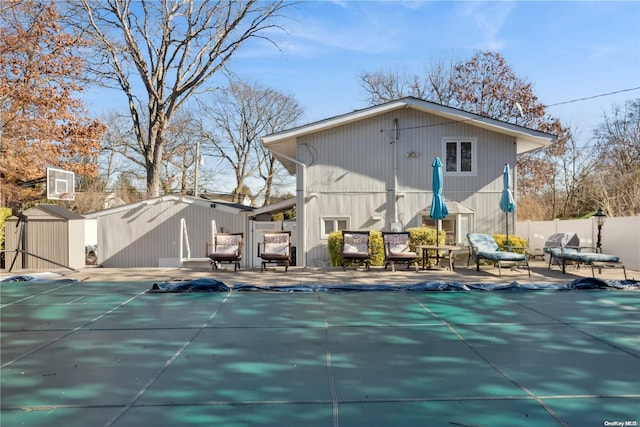 rear view of house featuring a patio, a covered pool, and a storage shed