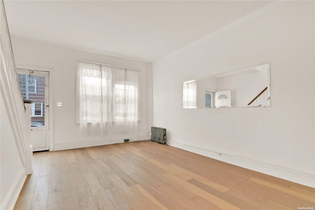 empty room with hardwood / wood-style floors and radiator heating unit