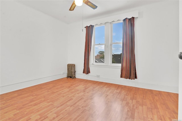 spare room with radiator heating unit, hardwood / wood-style flooring, and ceiling fan