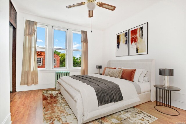 bedroom with radiator, ceiling fan, and hardwood / wood-style floors