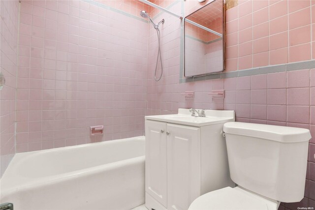 full bathroom with vanity, toilet, tile walls, and tiled shower / bath combo