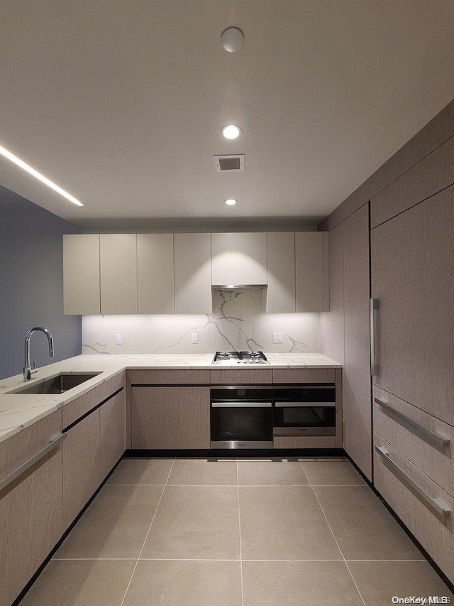 kitchen featuring sink, stainless steel oven, light tile patterned floors, and gas cooktop