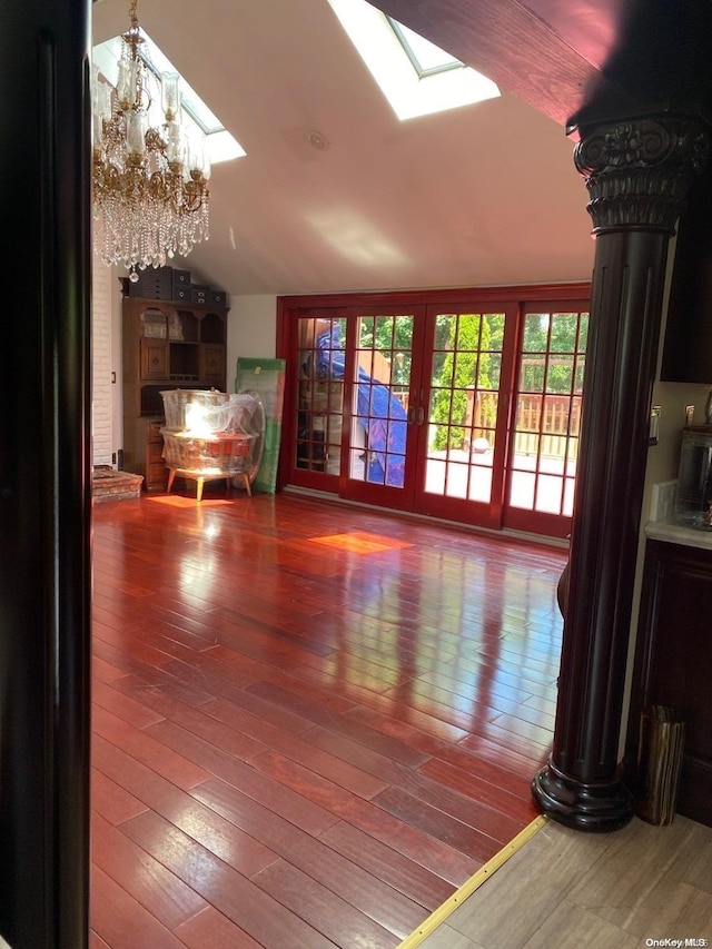 interior space with a chandelier, french doors, hardwood / wood-style flooring, and vaulted ceiling with skylight