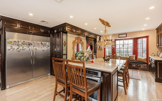 interior space with built in fridge, a kitchen breakfast bar, dark brown cabinetry, and light hardwood / wood-style flooring