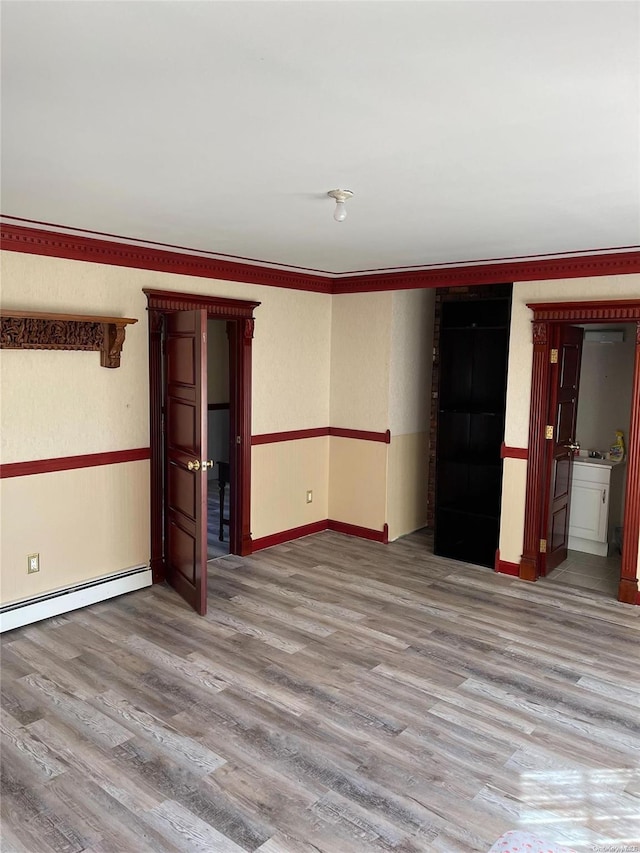 unfurnished room featuring wood-type flooring and a baseboard heating unit